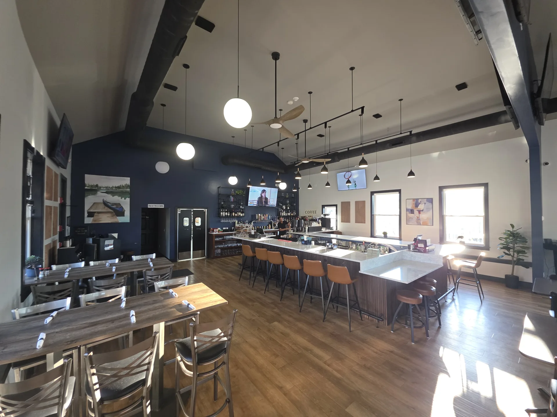 The bar at Fenimore's Table with tan leather stools, a white stone counter and a navy accent wall, beside a long high-top table The bar at Fenimore's Table with tan leather stools, a white stone counter and a navy accent wall, beside a long high-top table